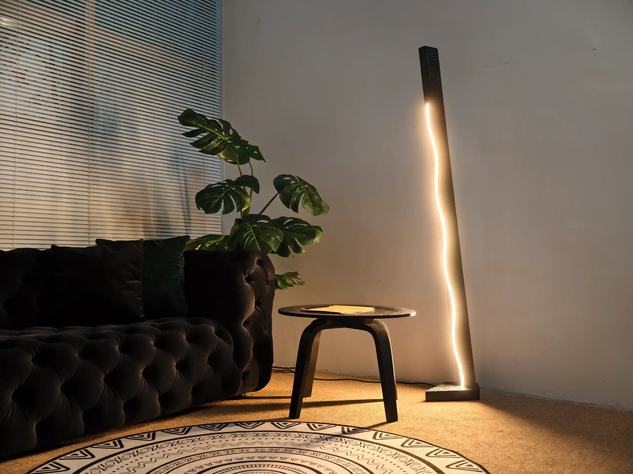 Lucky 7 Artistic Solid Wood Floor Lamp by FLOWLIGHT scaled – Flowlight Design This image captures the warm, inviting atmosphere created by the Blaze floor lamp from FLOWLIGHT DESIGN INC. This artistic, handmade lamp is crafted from natural solid wood in a distinctive medieval style, casting a warm glow that illuminates the surrounding space. The unique design features multiple wooden staves arranged around a central light source, creating intriguing shadows and a cozy ambiance, complemented by soft furnishings and a rustic log element.